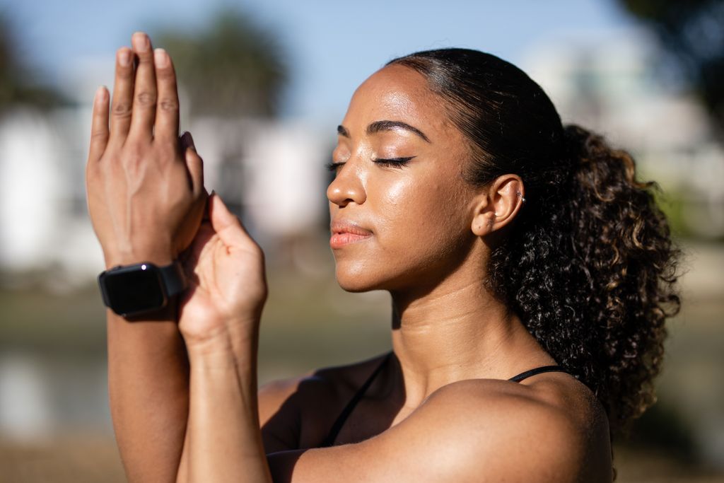 Close-up of a woman meditating with eyes closed, embodying relaxation and wellness outdoors.