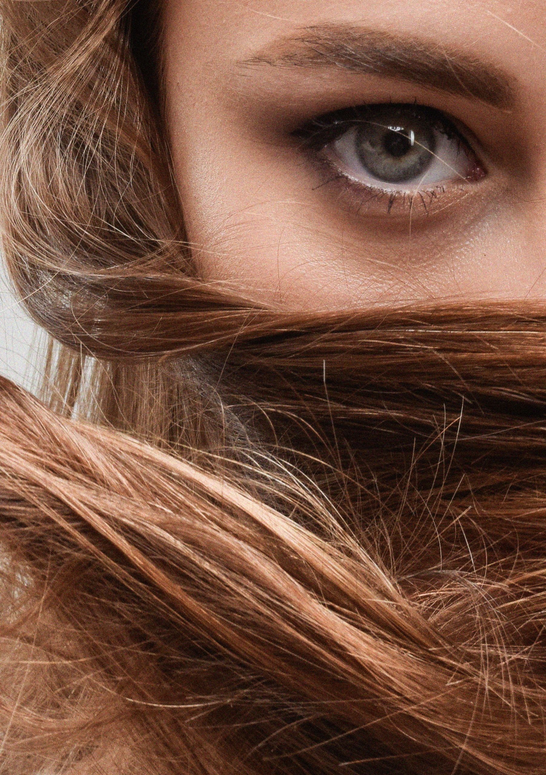 Intimate close-up of woman's eye partially obscured by her flowing hair.